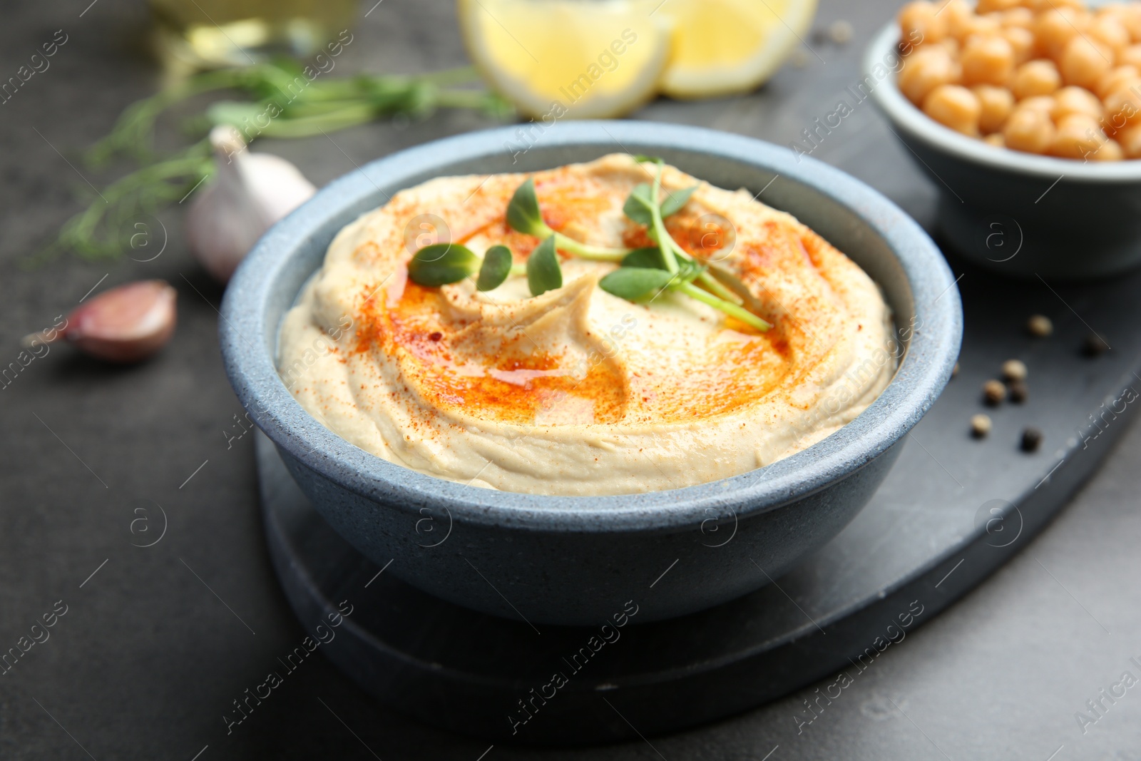 Photo of Delicious hummus with paprika served on dark grey table