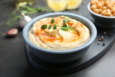 Photo of Delicious hummus with paprika served on dark grey table