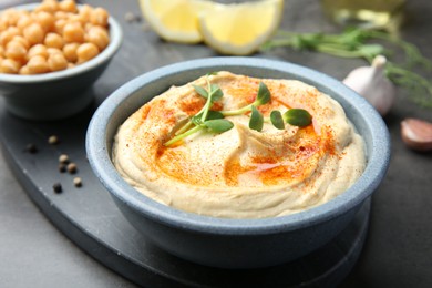 Photo of Delicious hummus with paprika and chickpeas served on dark grey table, closeup