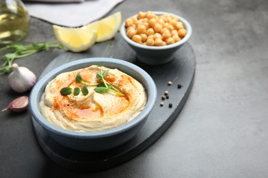 Photo of Delicious hummus with paprika and chickpeas served on dark grey table, space for text