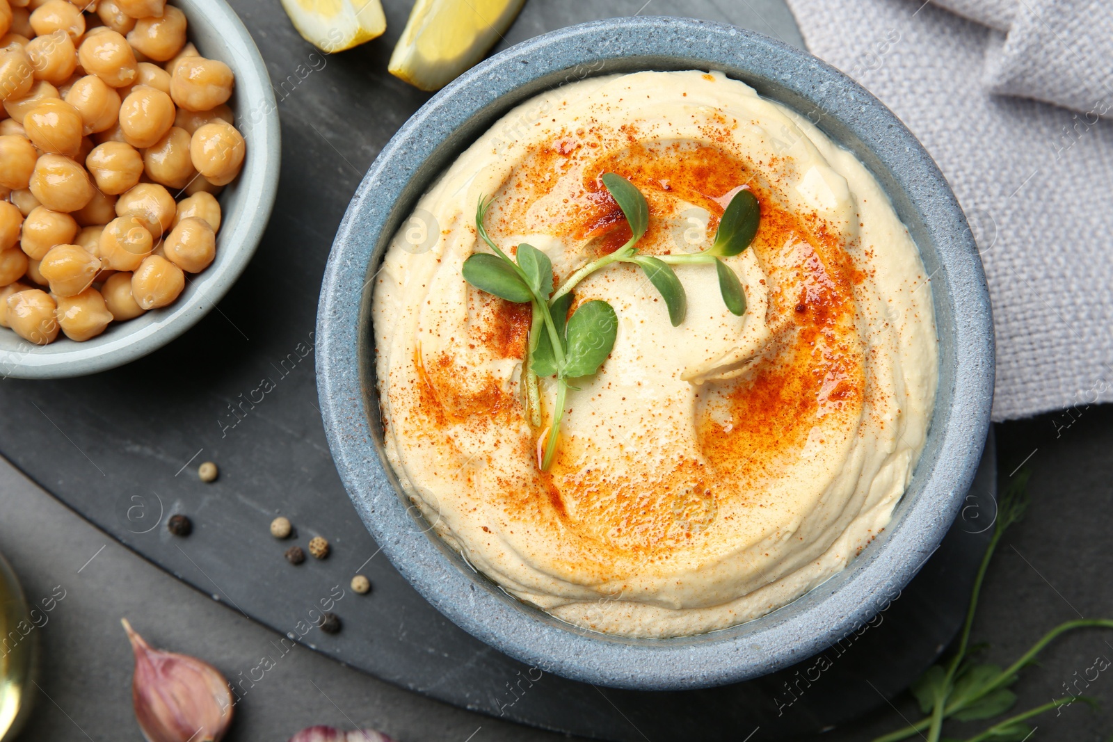 Photo of Delicious hummus with paprika and chickpeas served on dark grey table, flat lay.