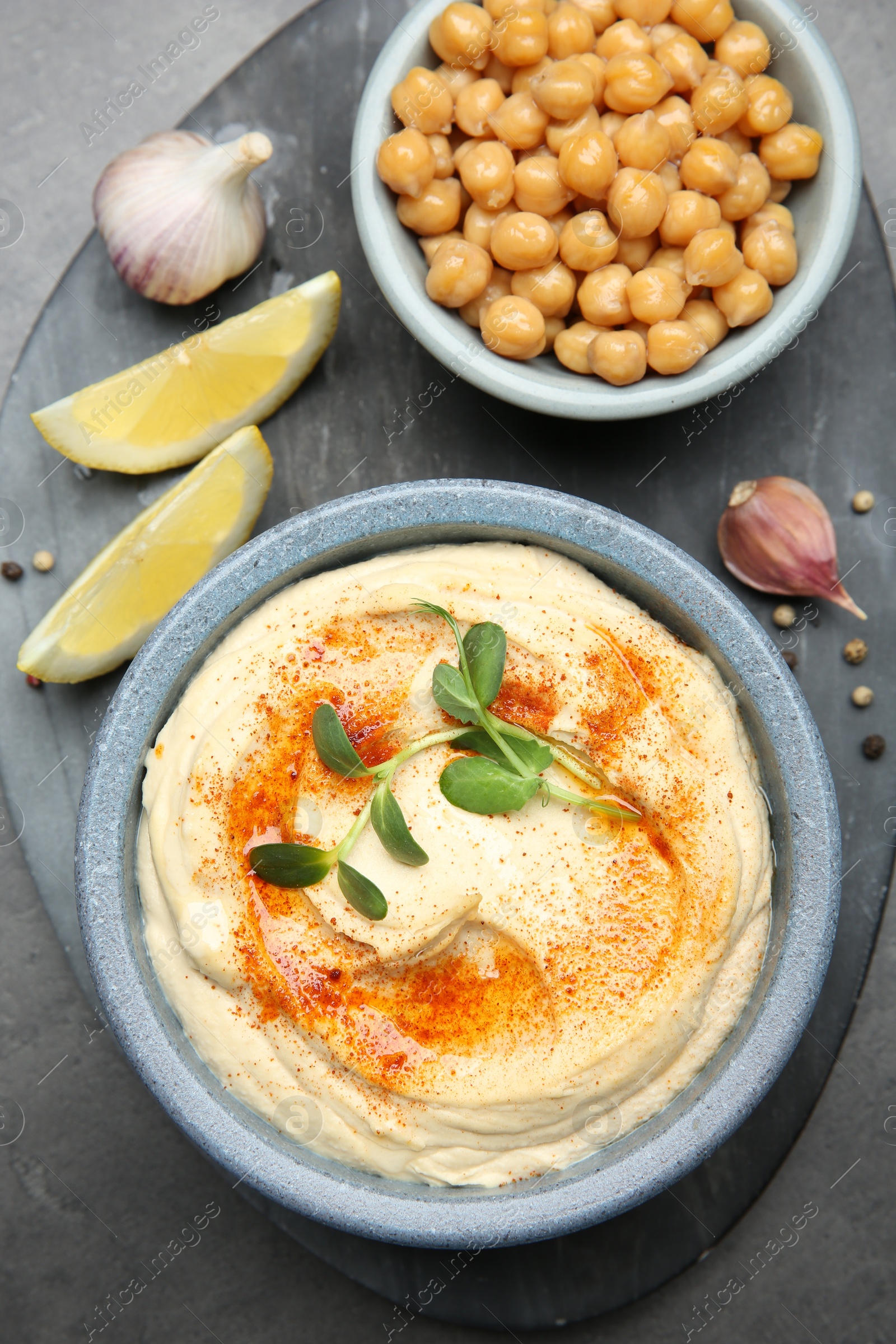 Photo of Delicious hummus with paprika and chickpeas served on dark grey table, flat lay