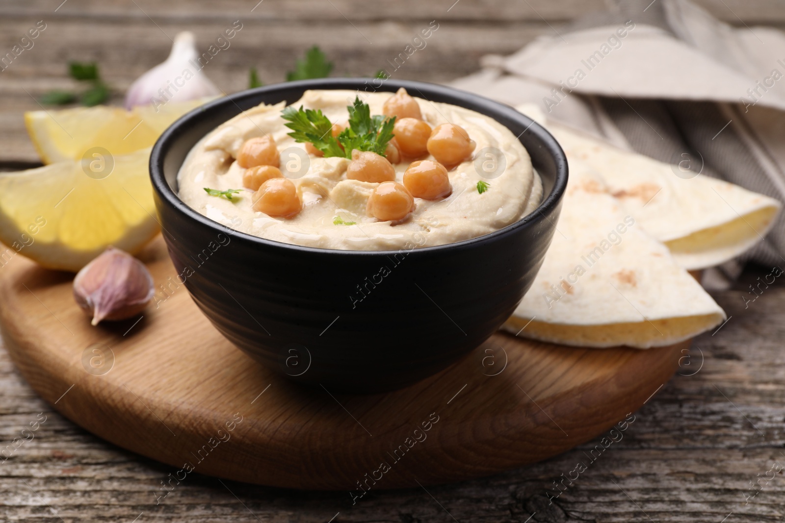 Photo of Delicious hummus with chickpeas and pita served on wooden table