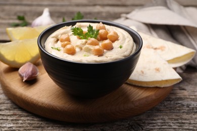 Delicious hummus with chickpeas and pita served on wooden table