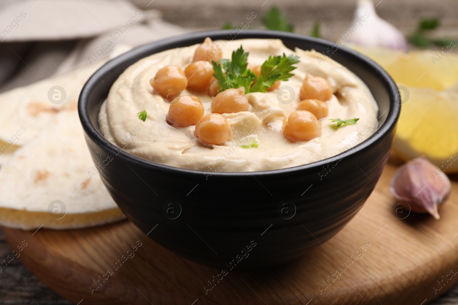 Photo of Delicious hummus with chickpeas and pita served on wooden table