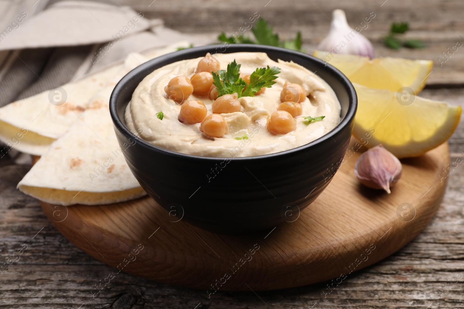 Photo of Delicious hummus with chickpeas and pita served on wooden table