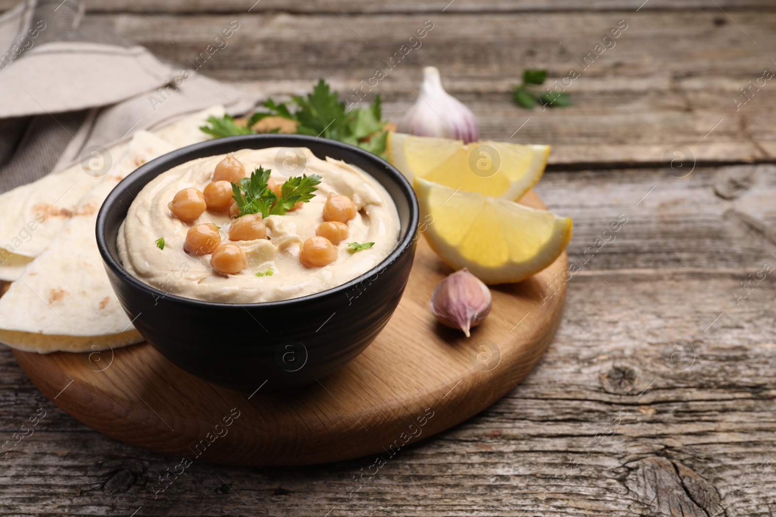 Photo of Delicious hummus with chickpeas and pita served on wooden table