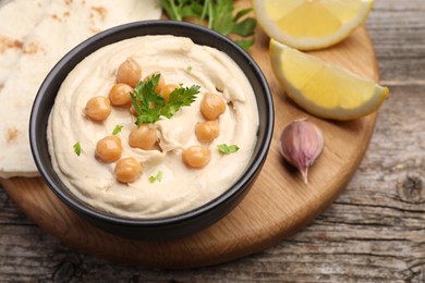 Photo of Delicious hummus with chickpeas and pita served on wooden table