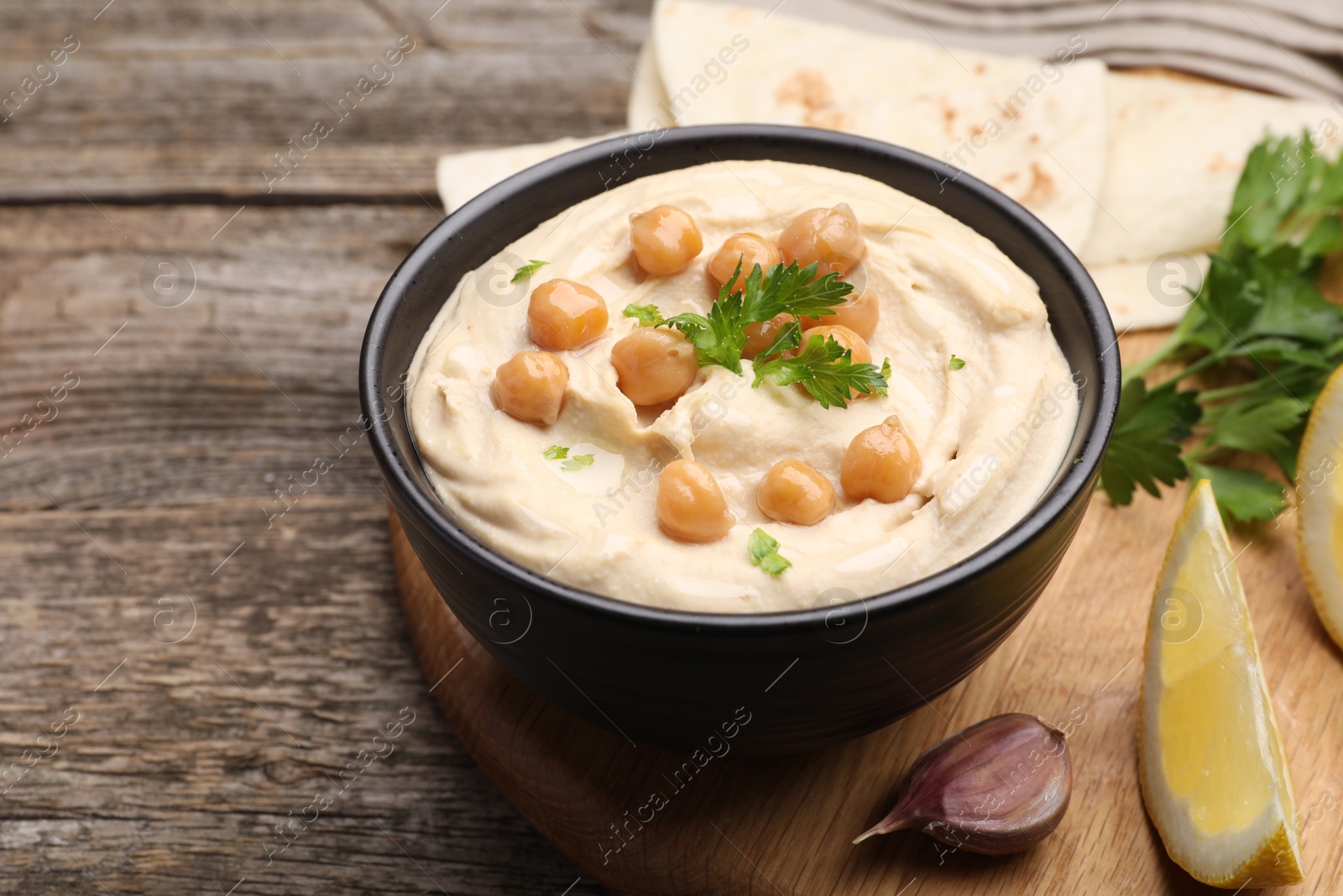 Photo of Delicious hummus with chickpeas and pita served on wooden table