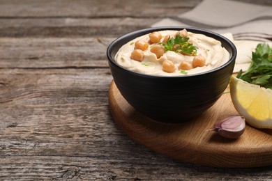 Photo of Delicious hummus with chickpeas and pita served on wooden table, space for text