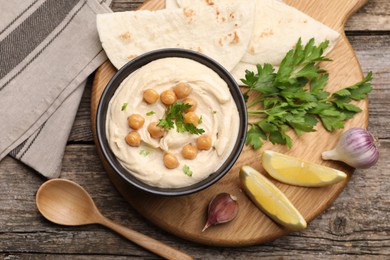 Delicious hummus with chickpeas and pita served on wooden table, flat lay