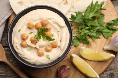 Delicious hummus with chickpeas and pita served on wooden table, flat lay