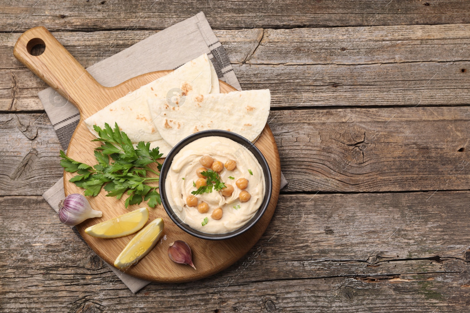 Photo of Delicious hummus with chickpeas and pita served on wooden table, flat lay. Space for text