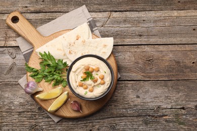 Delicious hummus with chickpeas and pita served on wooden table, flat lay. Space for text