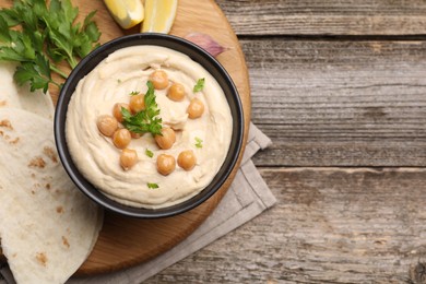 Delicious hummus with chickpeas and pita served on wooden table, flat lay. Space for text