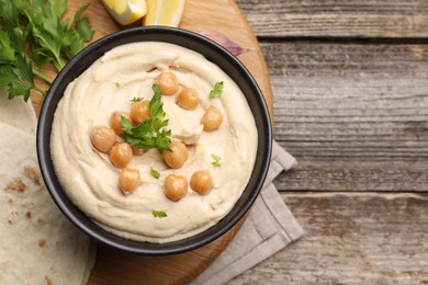 Delicious hummus with chickpeas and pita served on wooden table, flat lay. Space for text