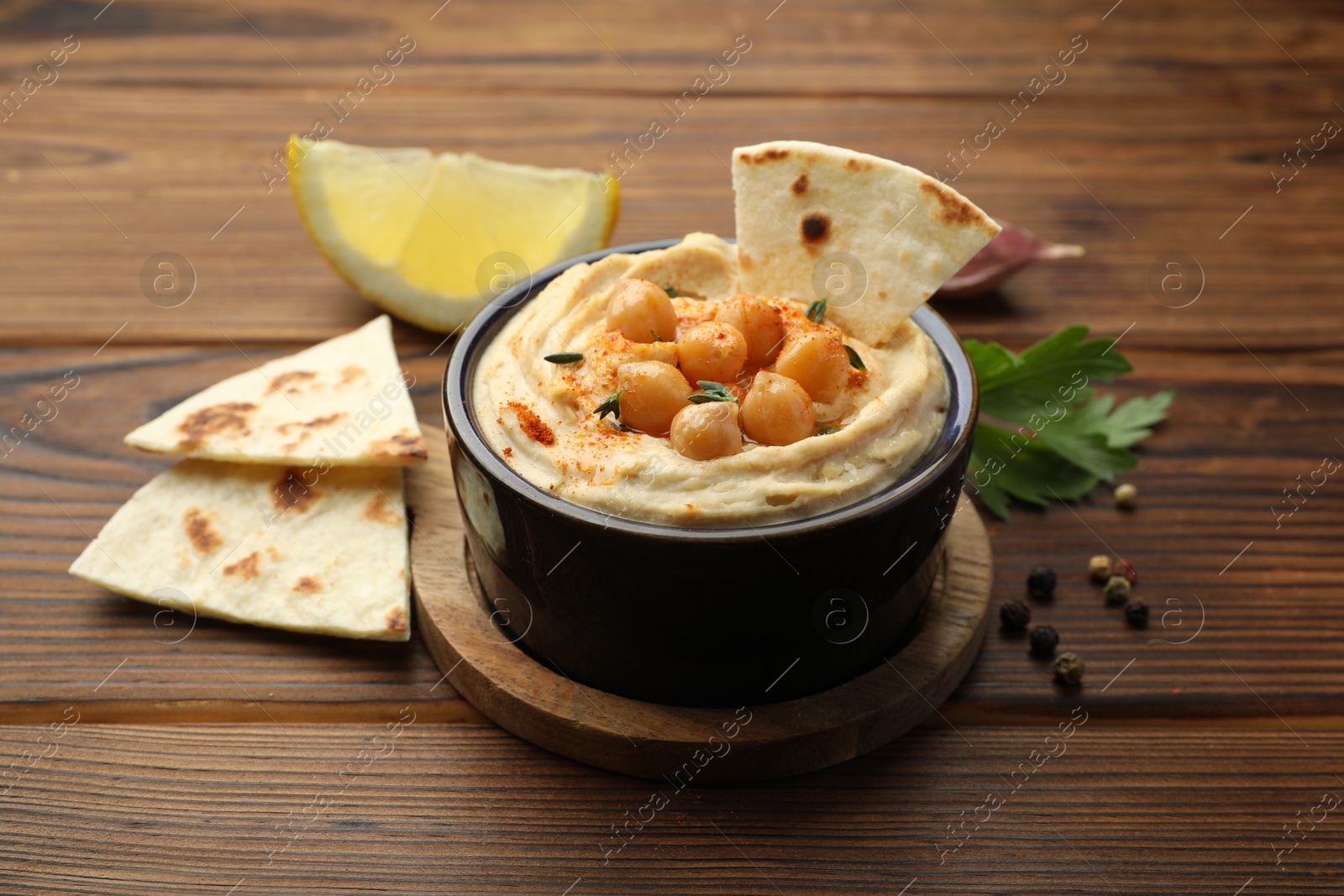 Photo of Delicious hummus with chickpeas and pita served on wooden table