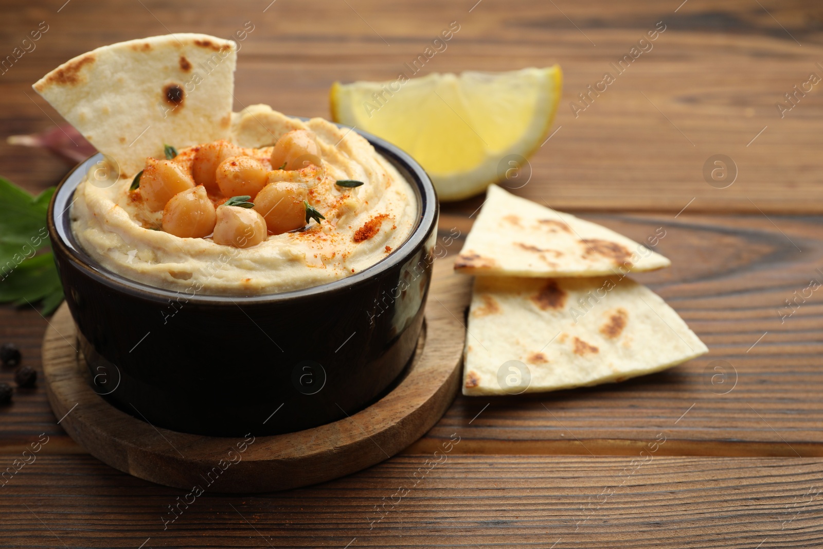 Photo of Delicious hummus with chickpeas and pita served on wooden table