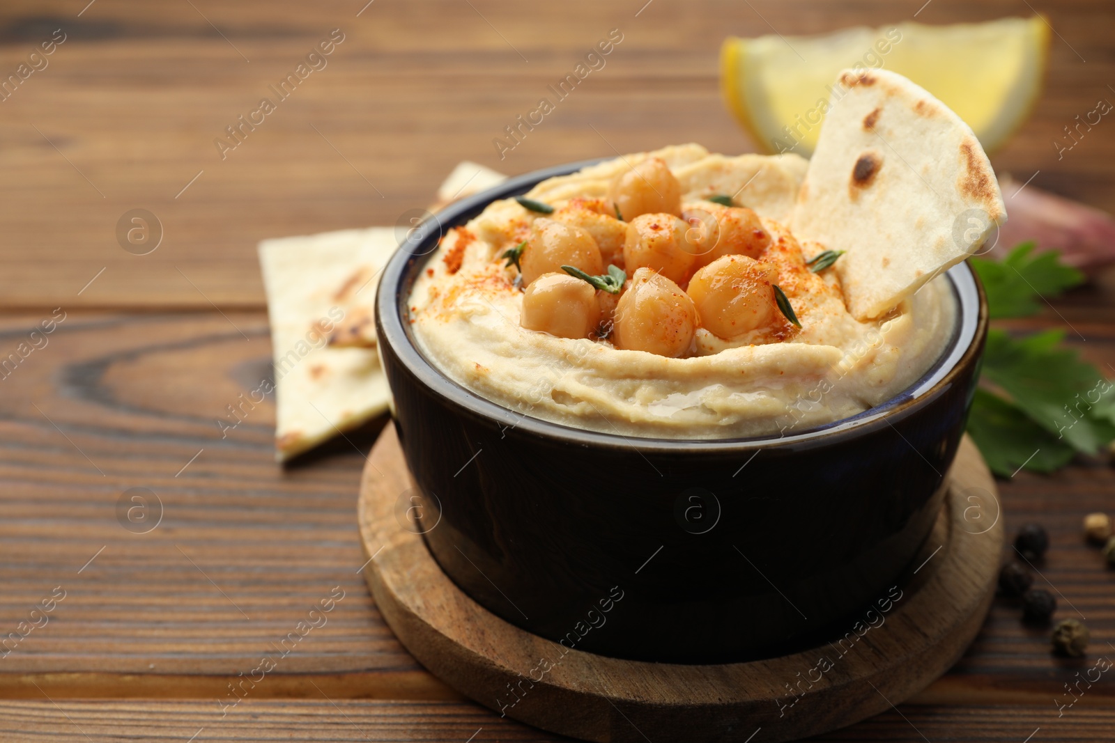 Photo of Delicious hummus with chickpeas and pita served on wooden table