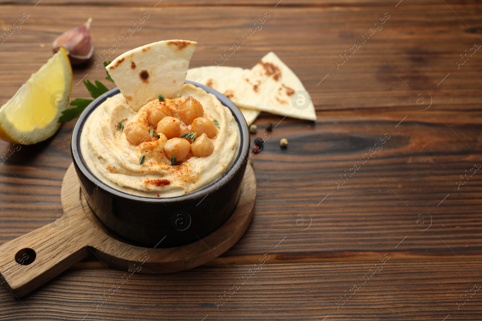 Photo of Delicious hummus with chickpeas and pita served on wooden table, space for text