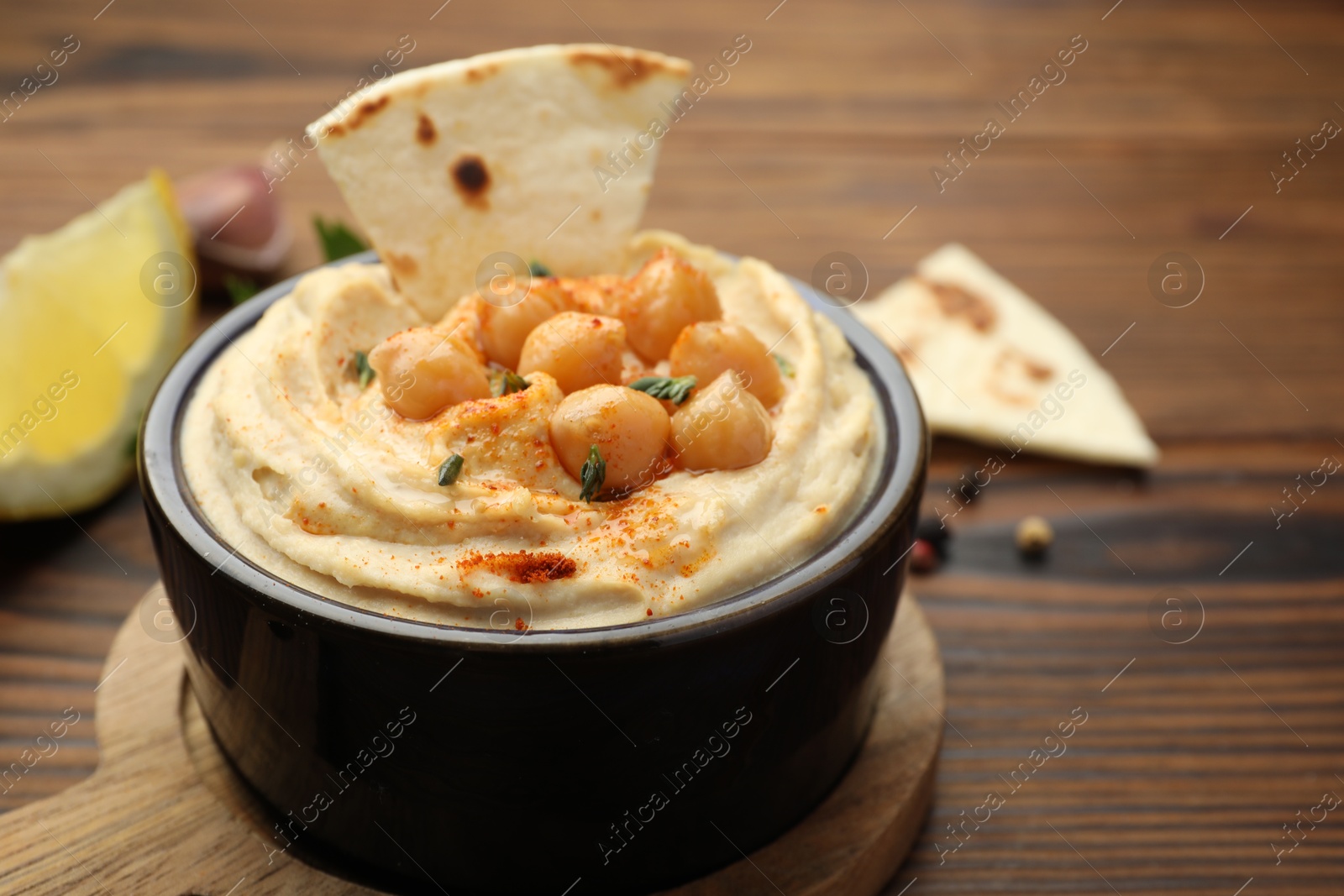 Photo of Delicious hummus with chickpeas and pita served on wooden table, closeup