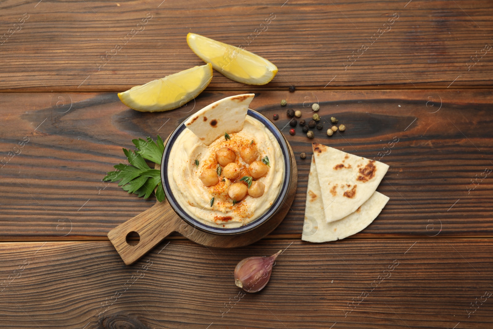 Photo of Delicious hummus with chickpeas and pita served on wooden table, flat lay