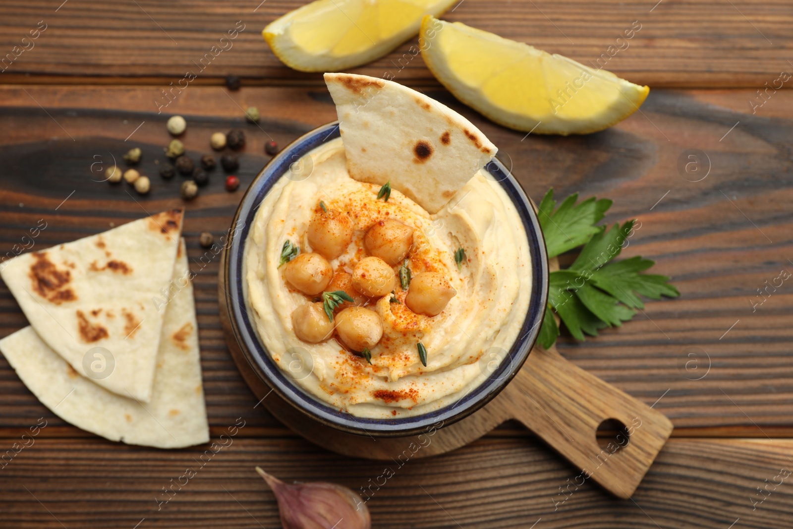 Photo of Delicious hummus with chickpeas and pita served on wooden table, flat lay