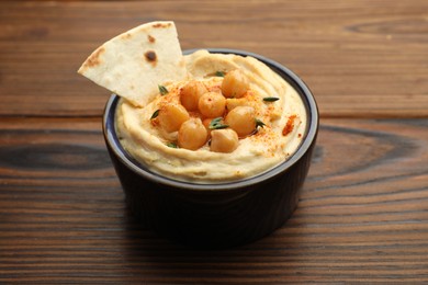 Photo of Delicious hummus with chickpeas and pita served on wooden table