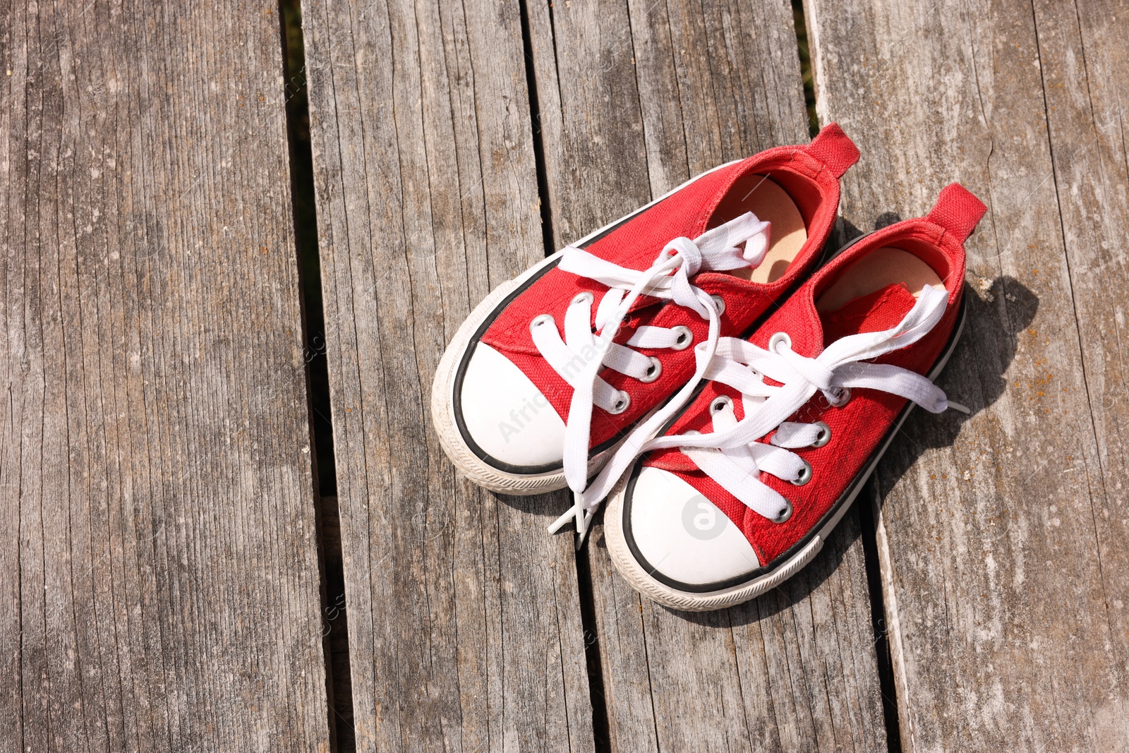 Photo of Pair of red shoes on wooden surface, top view. Space for text