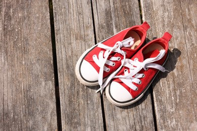 Pair of red shoes on wooden surface, top view. Space for text