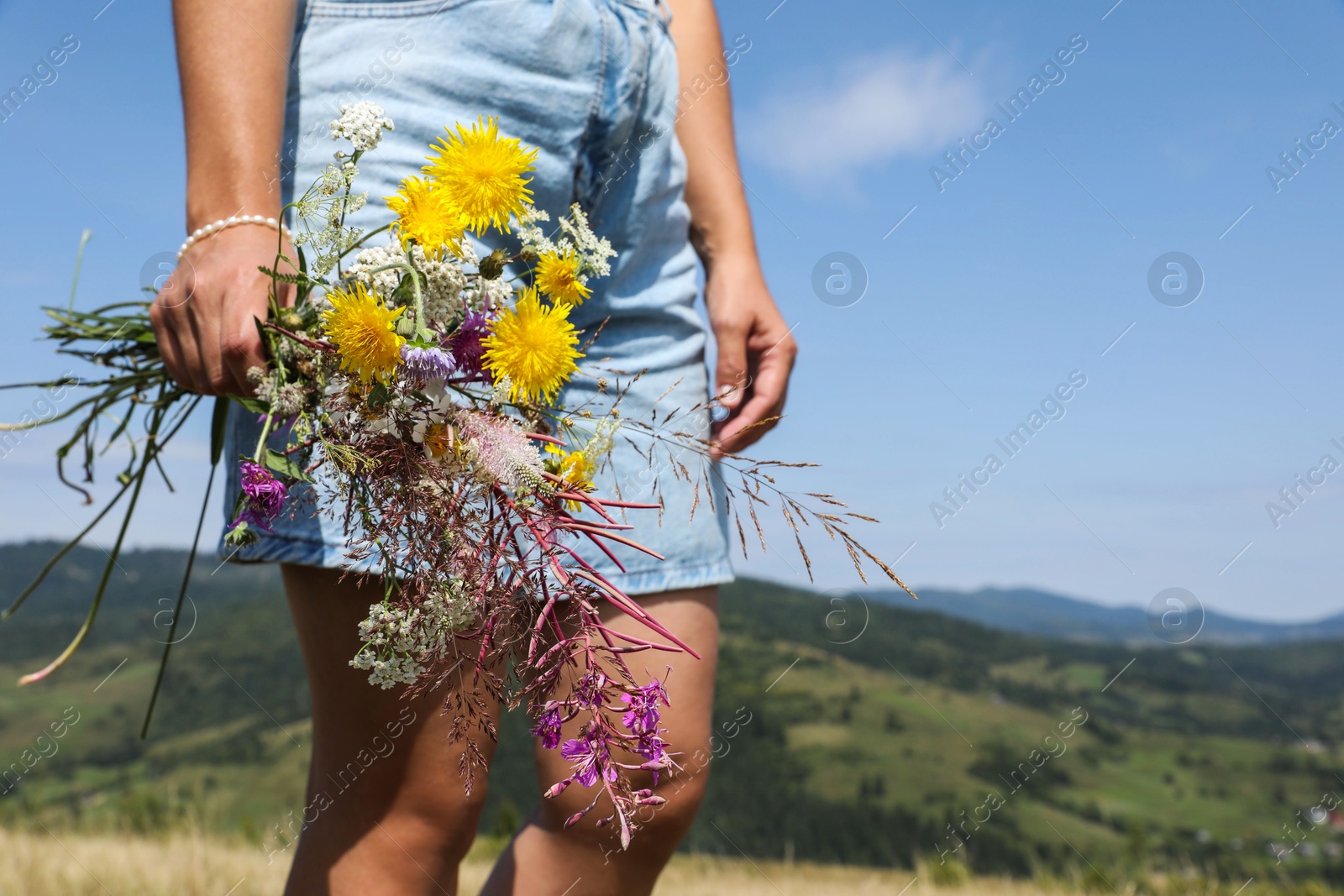 Photo of Woman holding bouquet of wild flowers outdoors, closeup