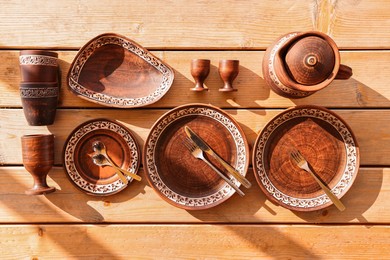 Photo of Different cutlery and tableware on wooden table, flat lay