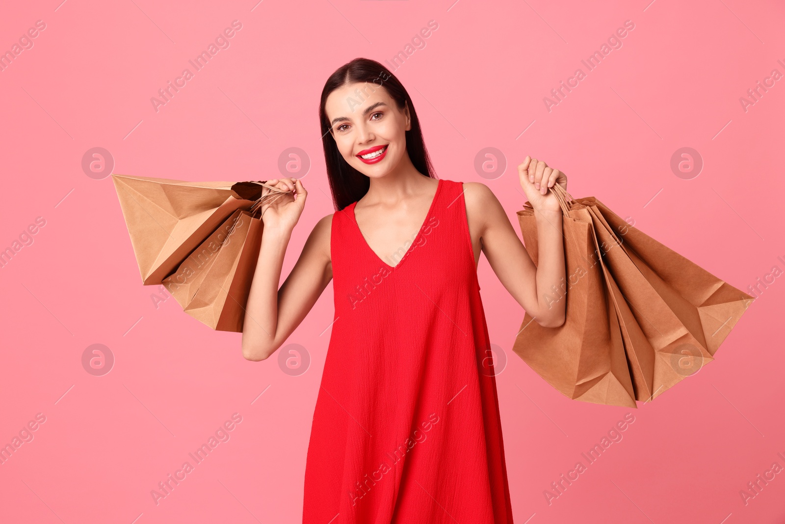 Photo of Smiling woman with shopping bags on pink background