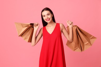 Photo of Smiling woman with shopping bags on pink background