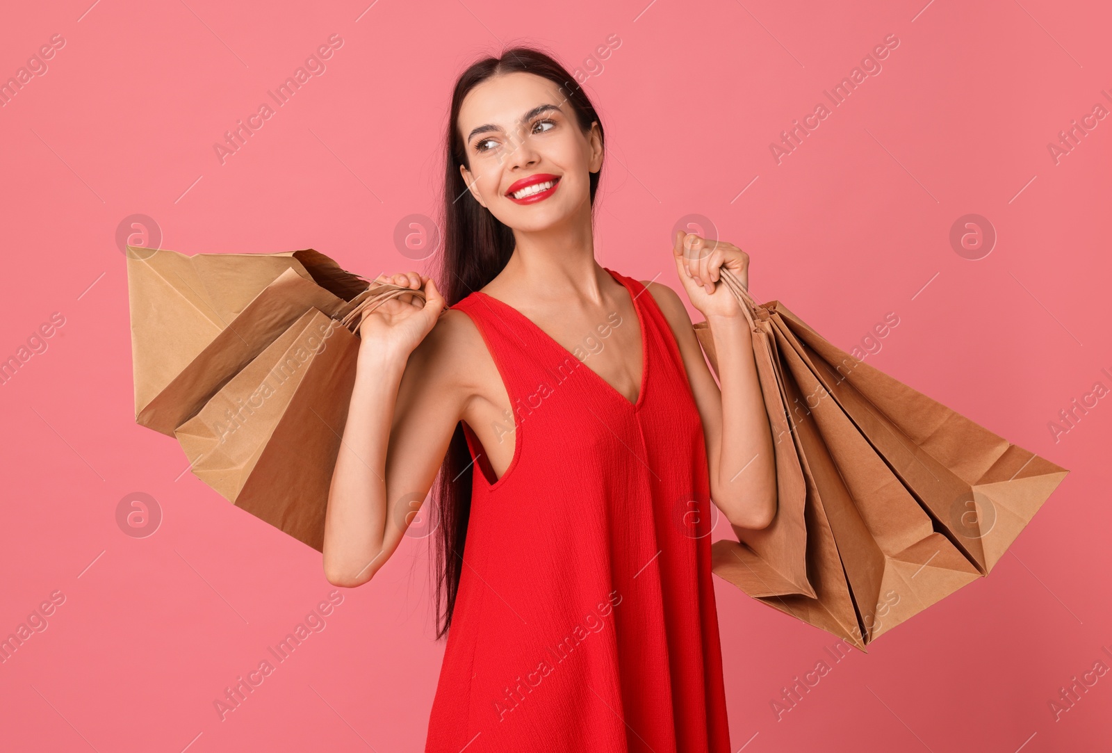 Photo of Smiling woman with shopping bags on pink background