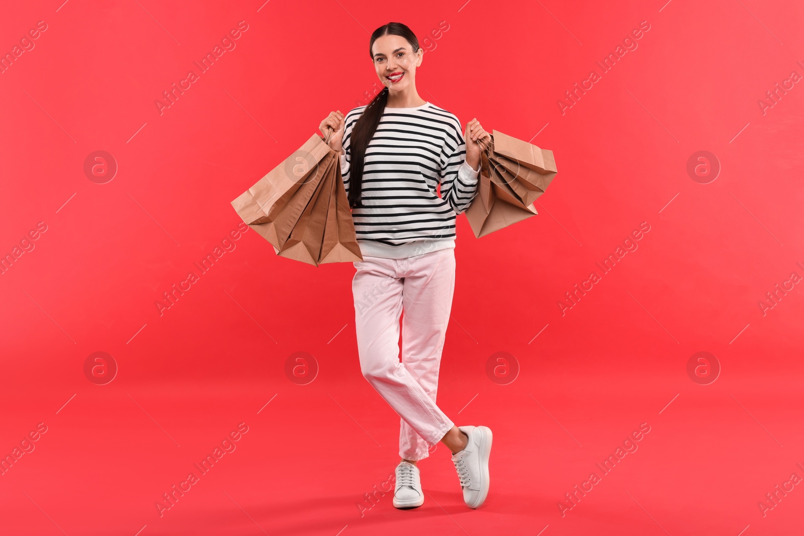 Photo of Smiling woman with shopping bags on red background