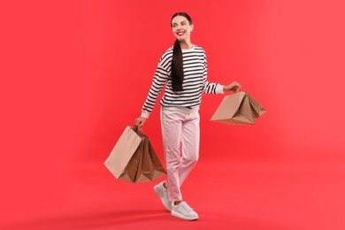 Smiling woman with shopping bags on red background