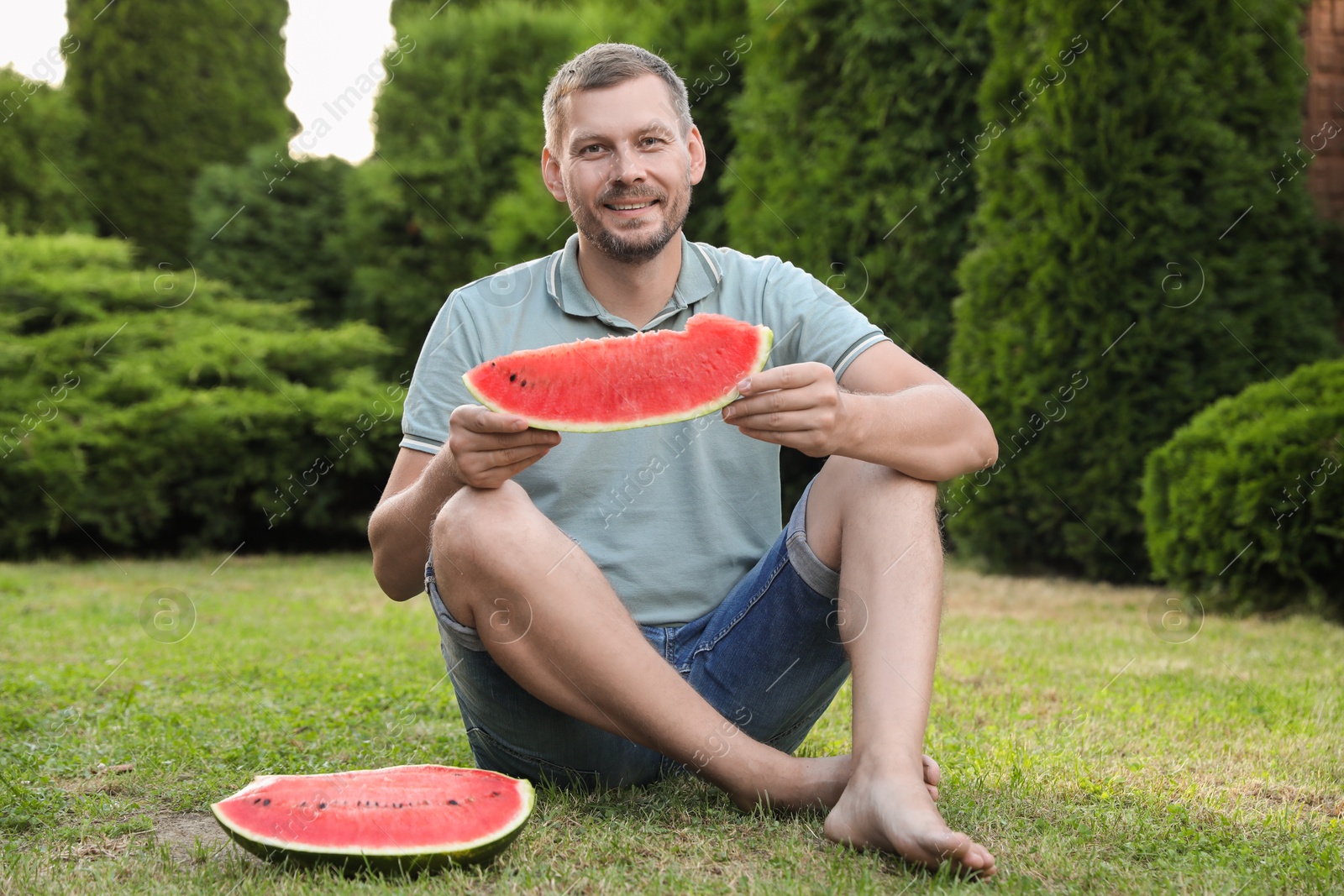 Photo of Happy man with slice of juicy watermelon outdoors