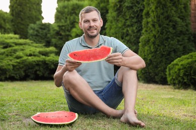 Happy man with slice of juicy watermelon outdoors