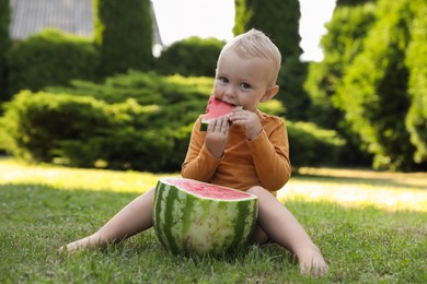 Photo of Cute little baby eating juicy watermelon on green grass outdoors