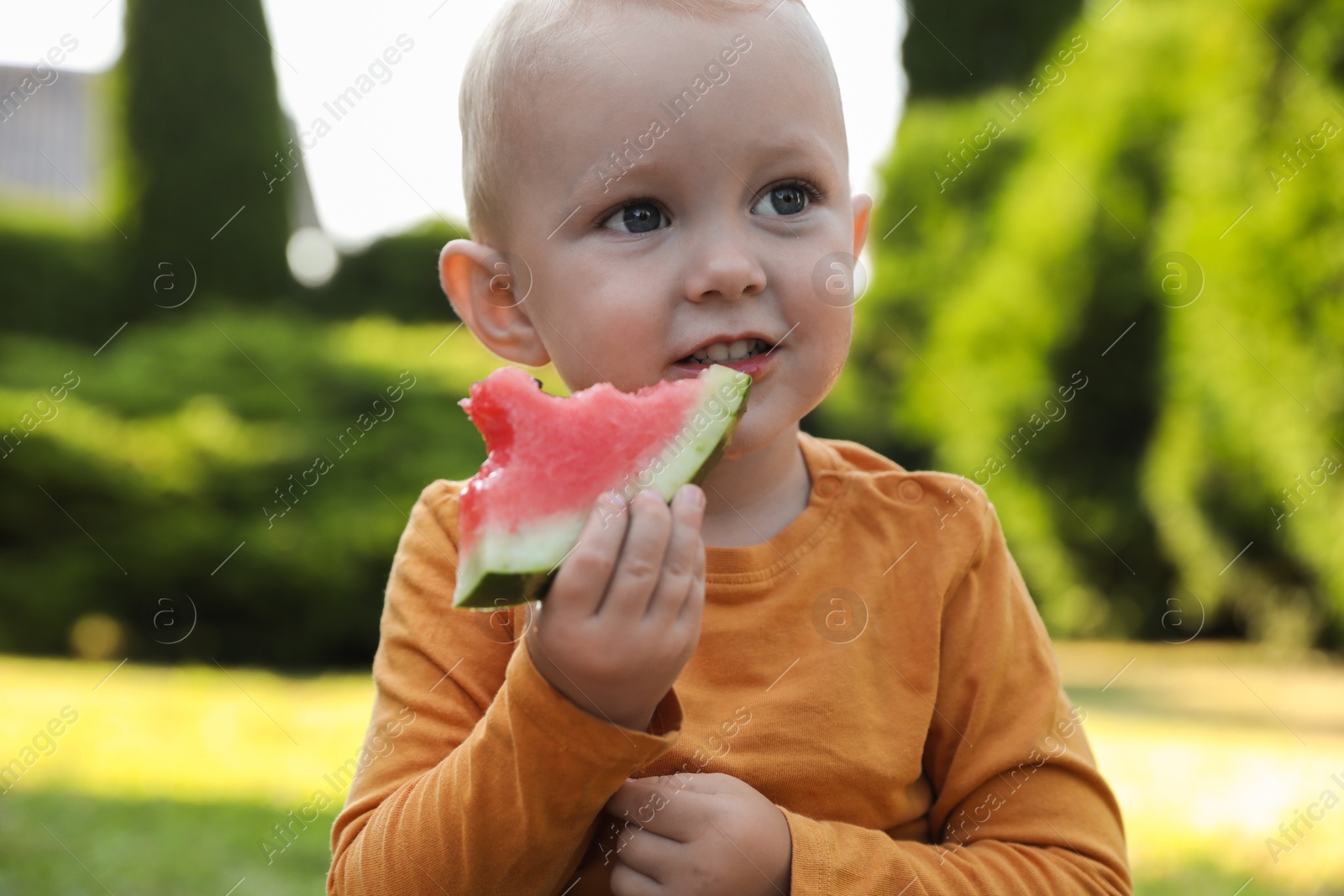 Photo of Cute little baby eating juicy watermelon outdoors