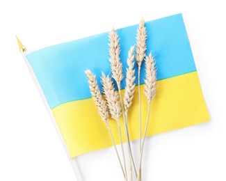 Photo of Ears of wheat and Ukrainian national flag isolated on white, top view