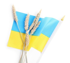 Ears of wheat and Ukrainian national flag isolated on white, above view