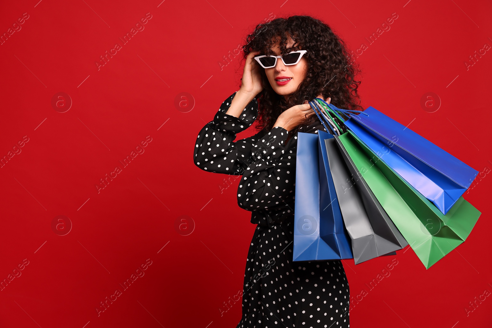 Photo of Beautiful woman with colorful shopping bags on red background. Space for text