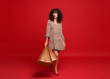 Beautiful woman with shopping bags on red background