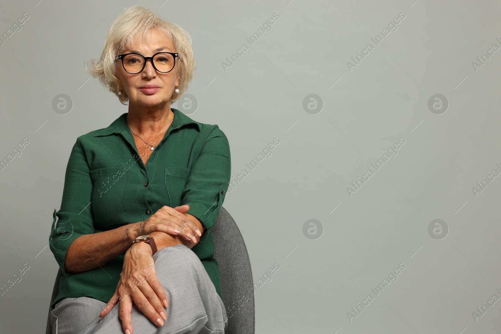 Photo of Beautiful senior woman sitting on chair against light grey background, space for text