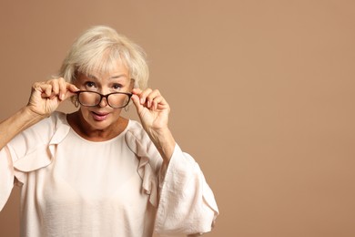 Photo of Portrait of beautiful senior woman on light brown background, space for text