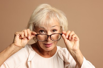 Photo of Portrait of beautiful senior woman on light brown background