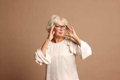 Photo of Portrait of beautiful senior woman on light brown background