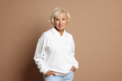 Portrait of beautiful senior woman on light brown background